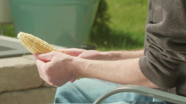 Man Brushing Off Corn on the Cob on Patio TILT UP CLOSE UP