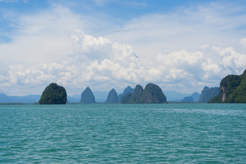 The karst rock of the island against a blue sky with clouds on a sunny day. Thailand Phang Nga National Park.