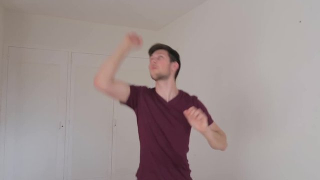 Young male dancing in a funny crazy way after hearing great news, still shot facing camera