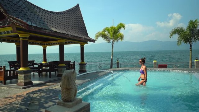Woman walking out of a pool in slo-mo at a resort on Lake Toba/Samosir Island in North Sumatra, Indonesia.