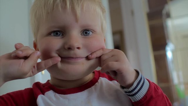 A cute child pulling a silly face with his fingers and posing for a photo. CLOSE UP.