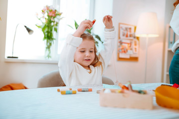 Girl wearing sweater playing with threads visiting mom in atelier