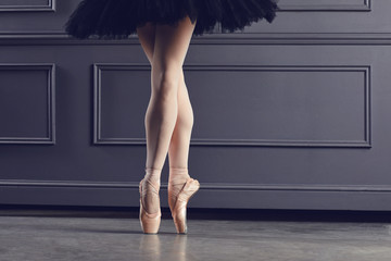 Legs of a ballerina on a black background. - obrazy, fototapety, plakaty