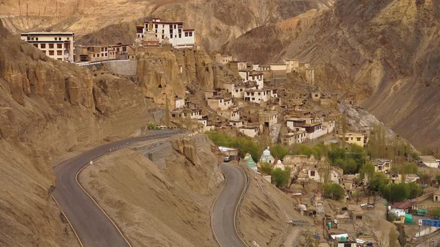 Wide high angle still shot of winding and curving tarmacked Kargil-Leh mountain Road , as you approach Lamayuru monastery, Ladakh. Spectacular view of mountain buildings.