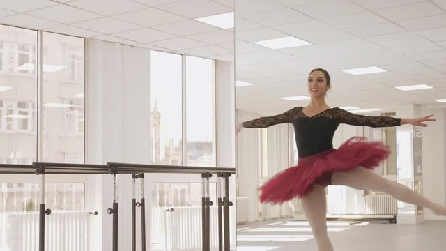 Professional European ballerina practicing in front of a mirror in a bright dancing studio