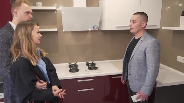 Caucasian Married Couple Staning in Kitchen of New Apartment Real Estate Property and They Talking to Male Realtor. Light Camera Movement