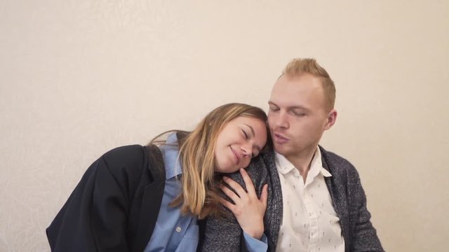 Happy Caucasian Couple Sitting on Bench By Wall While Female Holding Male With Hands and Lean Her Head on His Arm. Light Camera Movement