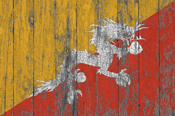 Flag of Bhutan painted on worn out wooden texture background.