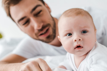 selective focus of bearded dad and curious baby