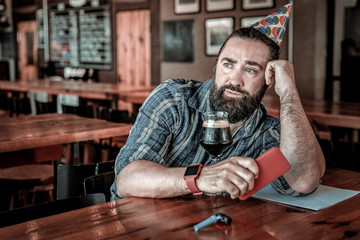 Lonely dark haired man enwrapped in thoughts in bar counter.