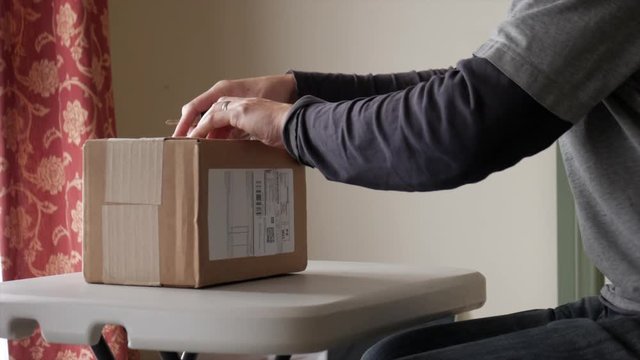 Man unboxing a parcel delivered from a courier. STATIC SHOT.