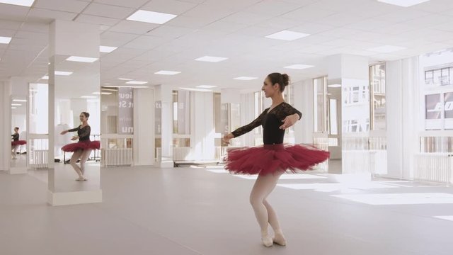 Slow motion arc shot of a smiling ballerina working on her pointe routine