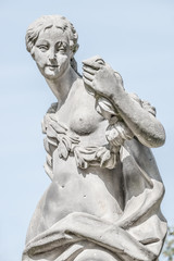 Ancient statue covered with moss and lichen of a sensual renaissance era woman in Potsdam, Germany