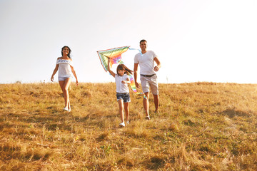 Happy family walking in nature at sunset in summer.