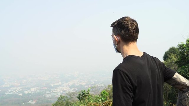 Young man standing on the observation deck and viewing the polluted city of Chiang Mai.