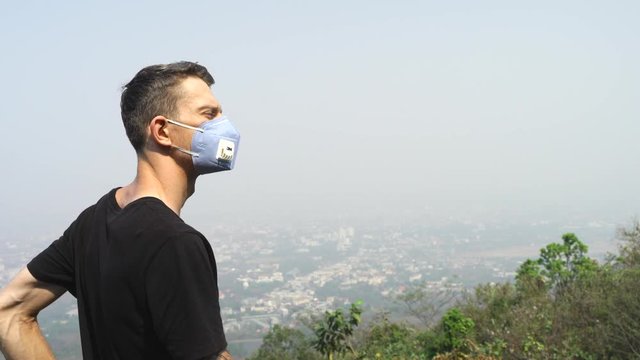 Chiang Mai Young man wearing a mask to avoid the toxic air inhalation. the Chiang -mai city scape with with pollution