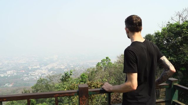 Man wearing a face mask standing on the observation point and watching the Chiang Mai city . City is completed toxic with a poor air quality.