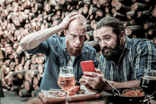 Two men being surprised at news they seeing on a smartphone.