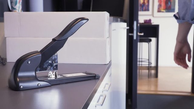 Close-up hands Caucasian office worker stapling papers. Indoor horizontal static locked off shot. Male using stapler, paperwork workplace.