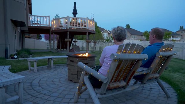 A Mature Couple Talking By The Fire Pit In Their Back Yard