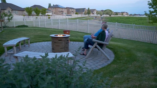 A Mature Couple Relaxing In Their Backyard Fire Pit