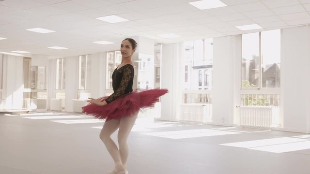 Professional ballerina smiling while practicing in a bright dance studio
