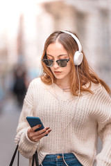 Beautiful young girl listens music while walking