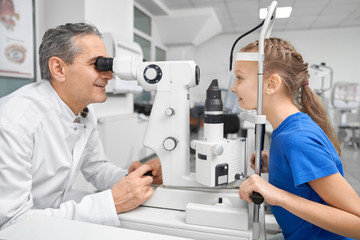 Doctor ophthalmologist examining eyes with test machine.