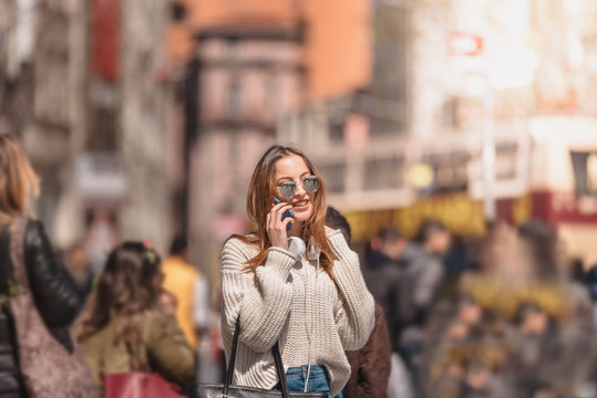 Beautiful woman uses smartphone while walking