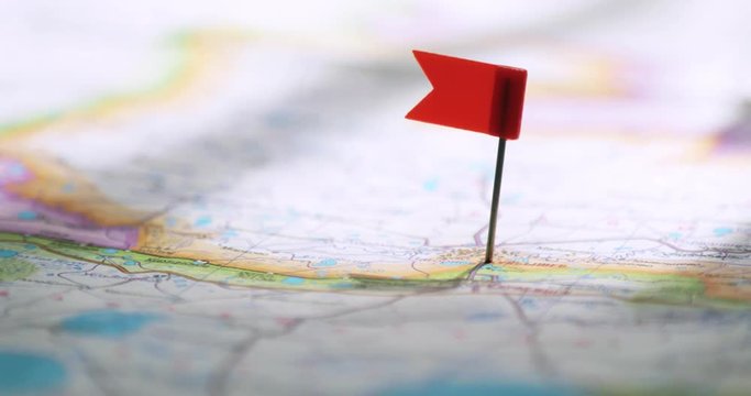 Man sticks flag pin on a map in necessary place to travel, hand closeup. World travel concept.