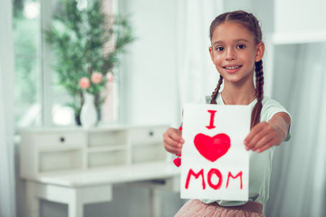 Nice-looking Afro-American girl showing picture with I love mom sign.