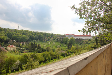 Fototapeta na wymiar Panoramic view of Strahov Monastery through the wall fence in Hradcany, Prague, Czech Republic. Diagonal wall on foreground close up