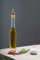 Olive oil in a bottle, with pepers, rosemary and garlic