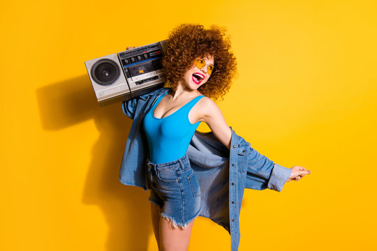 Close up side profile photo she her lady wavy styling curls old-fashioned tape recorder laugh laughter wear specs casual jeans denim shirt shorts tank top outfit clothes isolated yellow background