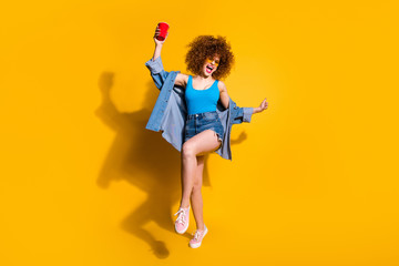Obraz na płótnie Canvas Full length body size photo funny funky she her lady wavy styling curls sing song beverage little drunk hang out wear specs casual jeans denim shirt shorts tank top clothes isolated yellow background