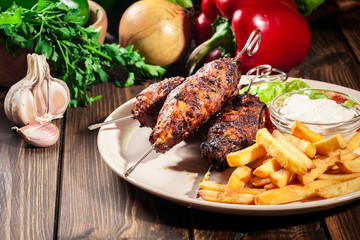 Grilled shish kebab served with fried chips and salad
