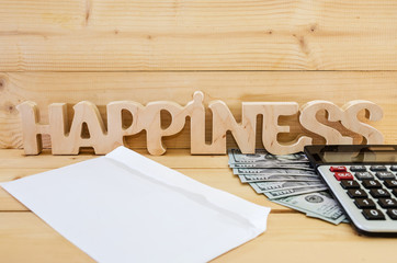 The wooden word "happiness" dollars, a calculator and a white envelope on a wooden background