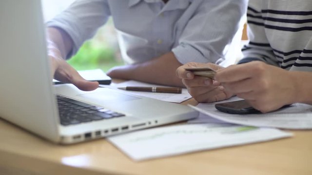 Mid section of man and woman using laptop and smart phone while making online payment through credit card at home