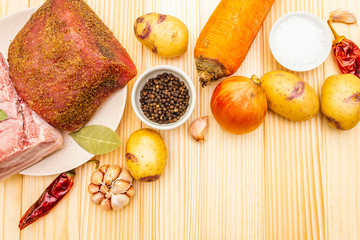 Ingredients for meat stew with potatoes and vegetables. Raw pork fillet, brisket, spices on a stone background, top view.