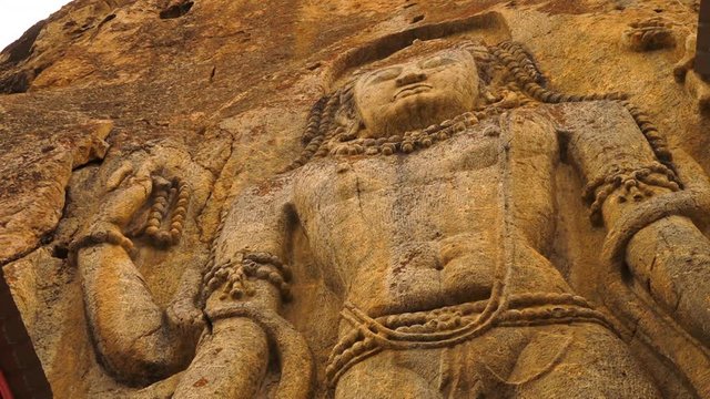 Extreme close up low angle still shot view of the upper part of Buddha chamba statue at  Mulbekh along Ladakh road. Sculpture of Buddha carved on  a stone, wearing and holding religious beads.