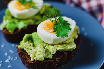 Healthy healthy snack (breakfast) - sandwich with avocado and egg on a gray plate.