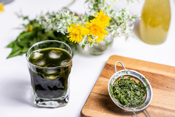 Dark green opaque drink in a glass with ice.