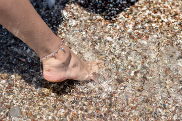 Female feet step on the sea wave