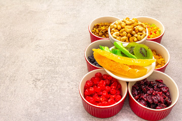 Dried and candied fruit and cashew nuts. Assorted in ceramic bowls on a stone background. Healthy...
