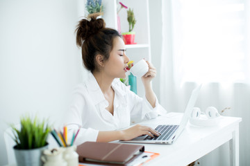 Beautiful young woman working on her laptop in her room.