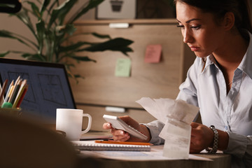 Female accountant calculating finances and working in the office.