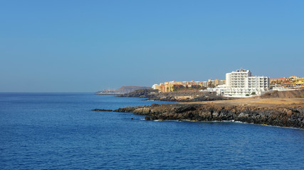 Fototapeta premium Summer, clear vistas towards San Blas and Golf del Sur, popular southern resorts in Tenerife, as seen from Playa Grande, in the small fishermen village of Los Abrigos, Tenerife, Canary Islands