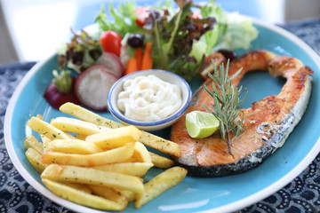 Roasted salmon steak , baked salmon with salad fresh vegetable pm wooden table