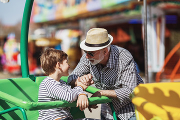 Grandfather and grandson having fun and spending good quality time together in amusement park.