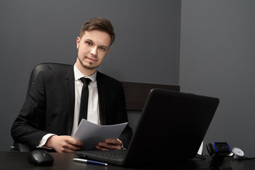 Young man at table with computer polygraph in grey room.